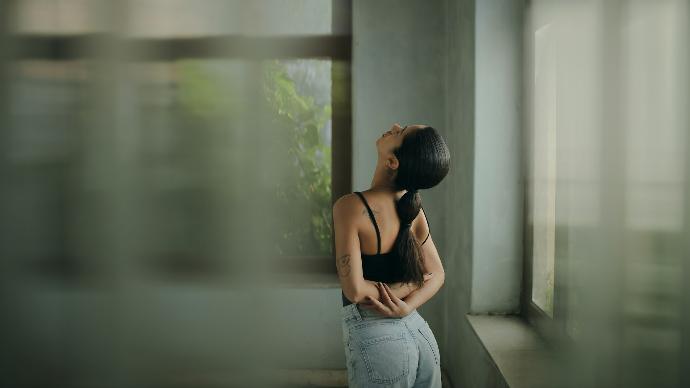 A woman leaning against a wall with her head in her hands