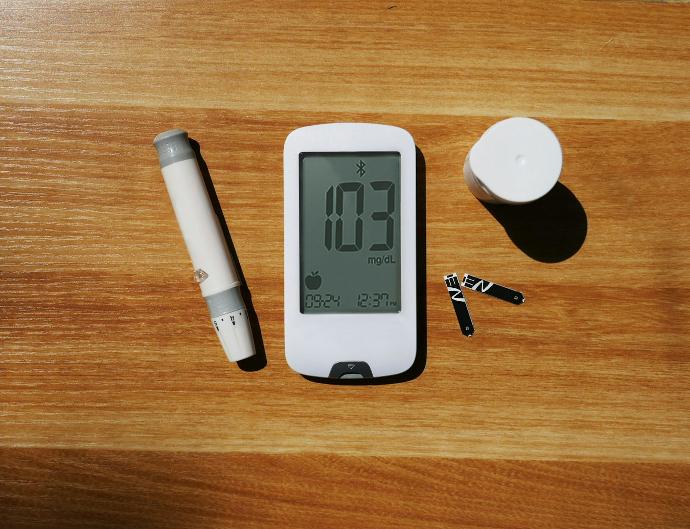 a wooden table topped with a smart phone and a pen